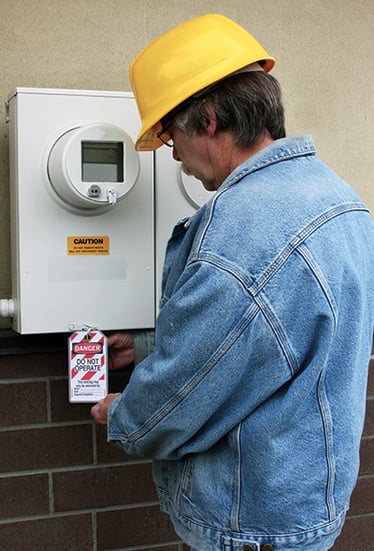 Worker attaching a lockout/tagout tag to an electrical box.