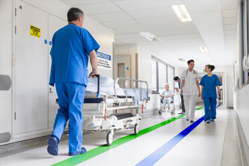 Floor marking and wayfinding signage pictured in a hospital hallway.