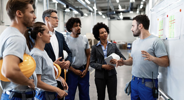 Workers meet in front of a whiteboard to organize their 5S efforts